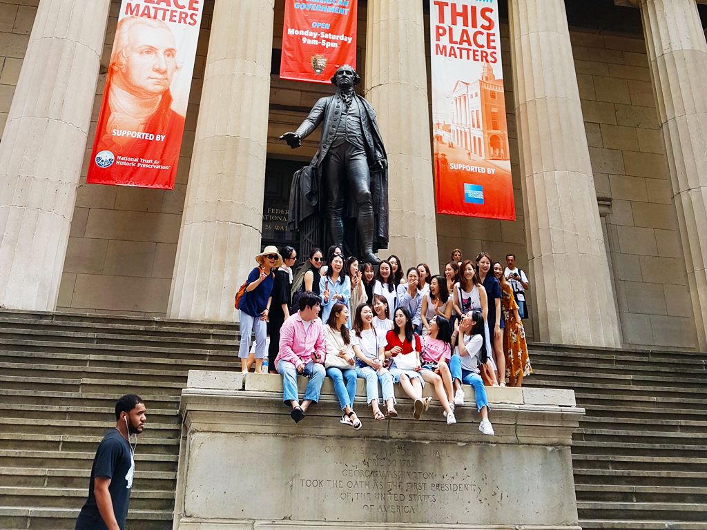 Turistas asiáticos sacándose una foto grupal frente a la estatua de Washington en el Federal Hall en Wall Street - Foto de AHM