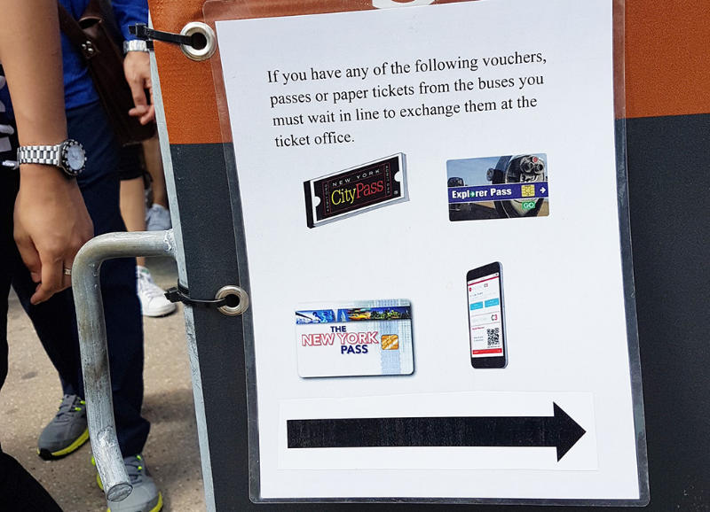 Letrero "Si tiene una tarjeta turística debe hacer la fila para canjear su entrada al ferry". Fila para las entradas con tarjetas de descuento en Castle Clinton, Battery Park - Foto de AHM