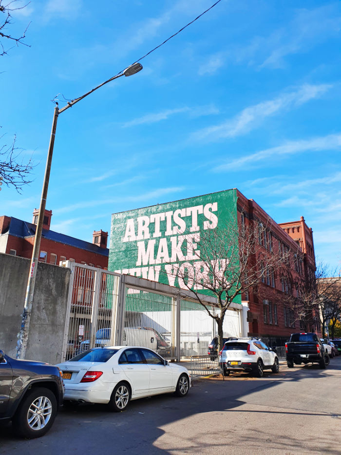 Edificio del MOMA PS1 con la muralla pintada en la que se lee "Artist make New York" - Foto de Andrea Hoare Madrid
