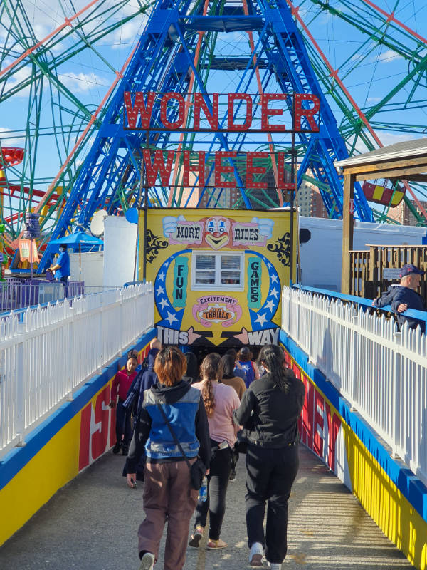 Gente de espaldas caminando desde la playa hasta la Wonder Wheel, la rueda de la fortuna de Coney Island, junto a Luna Park - Foto de Andrea Hoare Madrid