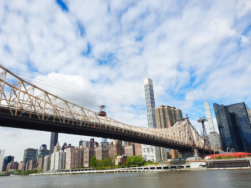 Vista de la orilla de Manhattan desde Roosvelt Island. Se ve un vagón del Tram cruzando el East River junto al Queensborough Bridge. Foto de Andrea Hoare Madrid