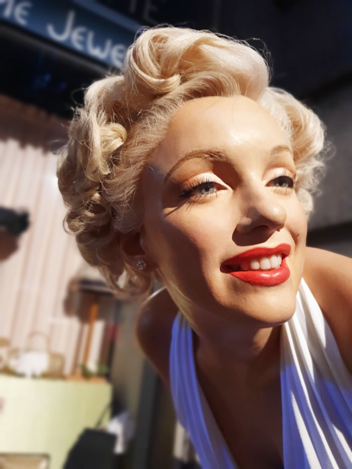 Detalle de la cabeza de Marilyn Monroe en la exhibición del Museo de Cera de Nueva York. Es una recreación de la icónica escena de Marilyn Monroe sobre un ventilador de metro en la película "The Seven Year Itch" (en español, "La comezón del séptimo año"), que fue estrenada en 1955. Esta famosa escena fue filmada en la intersección de Lexington Avenue y la calle 52nd en Manhattan, Nueva York.En la escena, Marilyn Monroe interpreta el papel de "La Chica", una atractiva vecina que vive en el apartamento del piso superior al protagonista, interpretado por Tom Ewell. Durante una calurosa noche de verano, "La Chica" está esperando el metro en la rejilla de ventilación del metro (subway grating) que sopla aire caliente desde abajo, lo que provoca que su icónico vestido blanco vuele a su alrededor, creando una imagen emblemática en la historia del cine.La imagen de Marilyn Monroe con su vestido blanco ondeando mientras sonríe coquetamente se ha convertido en una de las escenas más famosas y reconocibles de la historia del cine, y ha perdurado en la cultura popular a lo largo de los años. Foto de Andrea Hoare Madrid