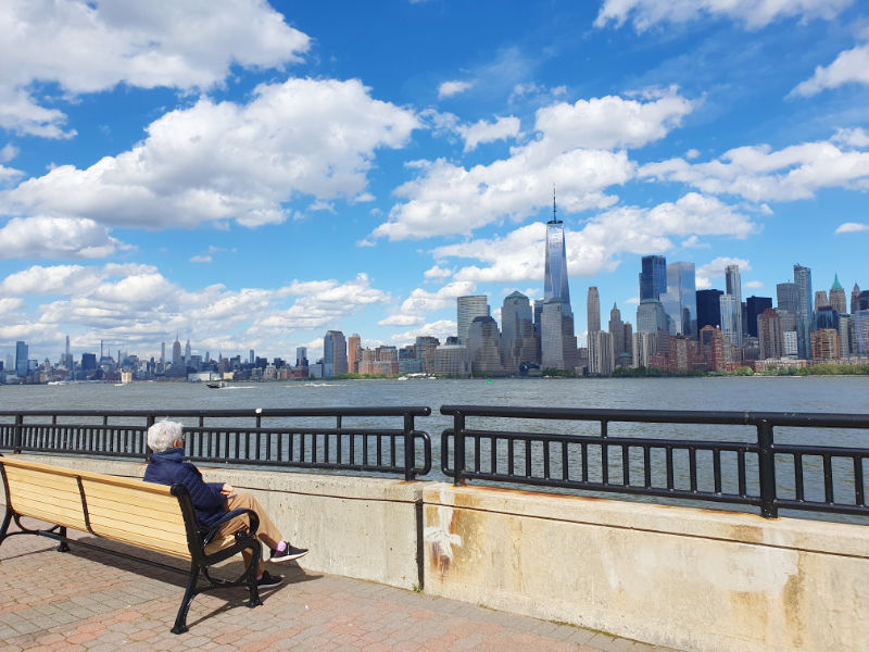 Persona sentada en una de las bancas del Liberty Walk en el Parque Liberty State de Jersey City mirando el horizonte de Manhattan al otro lado del Río Hudson - Foto de Andrea Hoare Madrid