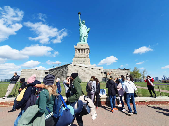 Turistas caminando al frente del pedestal de la Estatua de la Libertad en la Liberty Island - Foto de Andrea Hoare Madrid