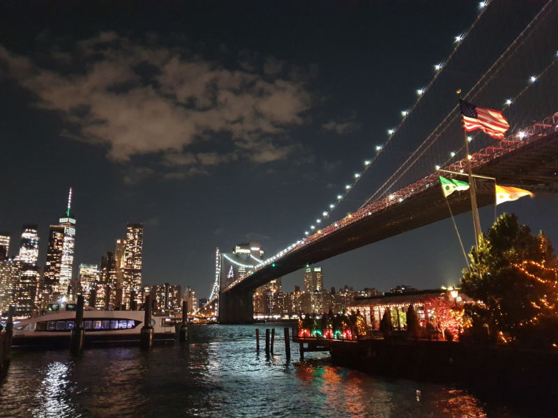 Fotografía de Andrea Hoare Madrid del Puente de Brooklyn iluminado a la derecha y de los rascacielos del sur de Manhattan a la Izquierda. Imagen tomada desde el Parque Brooklyn Bridge en DUMBO.